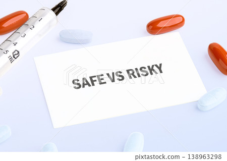 White card reading SAFE VS RISKY surrounded by diverse medical pills and a syringe, illustrating a choice between health safety and danger White card reading SAFE VS RISKY surrounded by diverse medical pills and a syringe, illustrating a choice between health safety and danger 138963298