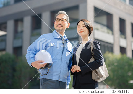 一名身穿工作服的男子和一名身穿西裝的女子 一名身穿工作服的男子和一名身穿西裝的女子 138963312