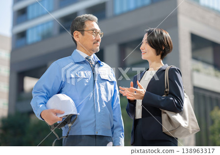 一名身穿工作服的男子和一名身穿西裝的女子 一名身穿工作服的男子和一名身穿西裝的女子 138963317