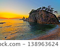 A view of the sunset sinking below the horizon of the Sea of Japan against a clear, bright sunset sky, and the Megane-iwa rock formation in Sasagawa-nagare. Ver3 138963624