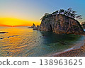 A view of the sunset sinking below the horizon of the Sea of Japan against a clear, bright sunset sky, and the Megane-iwa rock formation in Sasagawa-nagare. Ver1 138963625