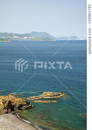 Scenic coastal landscape with turquoise water, rocky shore and distant tropical islands under a clear sky, creating a calm and peaceful seaside view in Asia. Scenic coastal landscape with turquoise water, rocky shore and distant tropical islands under a clear sky, creating a calm and peaceful seaside view in Asia. 138963783