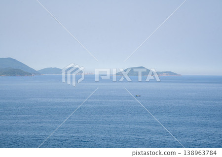 Calm seascape with distant tropical islands and a small fishing boat on the horizon, creating a peaceful and minimalistic coastal scene in Asia. Calm seascape with distant tropical islands and a small fishing boat on the horizon, creating a peaceful and minimalistic coastal scene in Asia. 138963784