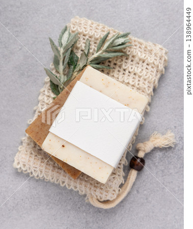 Handmade solid soap bars set with blank label mockup on soap saver bag near green leaves top view Handmade solid soap bars set with blank label mockup on soap saver bag near green leaves top view 138964449