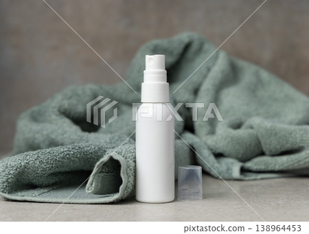 White spray cosmetic bottle mockup near sage green bath towel on stone. Unbranded blank packaging 138964453