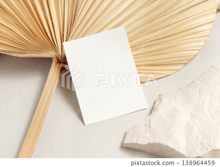 Blank card mockup with dried palm leaf on beige stone top view, boho wedding stationery Blank card mockup with dried palm leaf on beige stone top view, boho wedding stationery 138964459