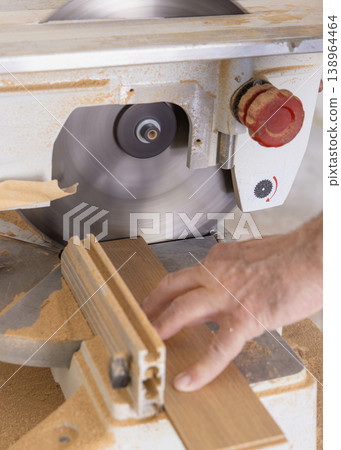 Construction worker cutting parquet plank with circular table saw during flooring installation Construction worker cutting parquet plank with circular table saw during flooring installation 138964464