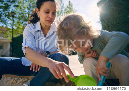 Mother and Young Child Playing Together in Sand Outdoors on a Sunny Day Mother and Young Child Playing Together in Sand Outdoors on a Sunny Day 138964570