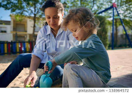Mother and Toddler Playing Together in Park Sandbox on Sunny Day 138964572