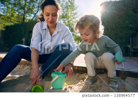 Mother and Toddler Playing Together in Sandbox Outdoors on Sunny Day 138964577