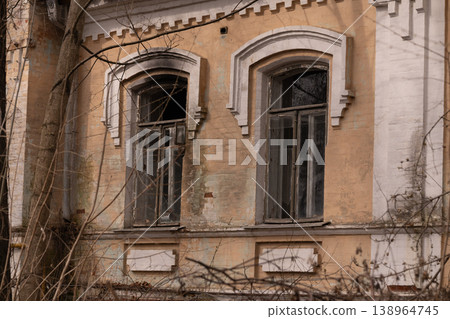 Old Abandoned Mansion Facade with Arched Windows and Decaying Plaster in Earthy Tones Old Abandoned Mansion Facade with Arched Windows and Decaying Plaster in Earthy Tones 138964745