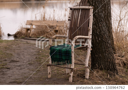 Rustic Birch Wood Chair with Green Plaid Blanket by a Calm Lake in Autumn Landscape Rustic Birch Wood Chair with Green Plaid Blanket by a Calm Lake in Autumn Landscape 138964762