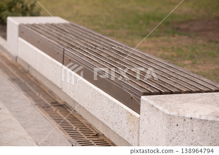 Empty Wooden Slatted Bench on Stone Base in Outdoor Public Park Setting Empty Wooden Slatted Bench on Stone Base in Outdoor Public Park Setting 138964794