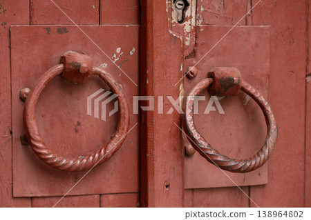 Red Vintage Wooden Double Door with Ornate Metal Ring Knockers and Distressed Texture Red Vintage Wooden Double Door with Ornate Metal Ring Knockers and Distressed Texture 138964802