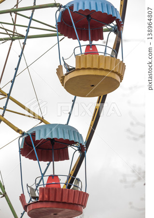 Low Angle View of Colorful Amusement Park Ferris Wheel Gondolas Against Overcast Sky Low Angle View of Colorful Amusement Park Ferris Wheel Gondolas Against Overcast Sky 138964807