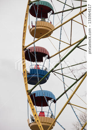 Colorful Ferris Wheel Gondolas Rotating Against Cloudy Sky in Amusement Park 138964817