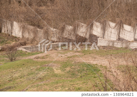 Concrete Retaining Wall with Dry Bare Vegetation and Trees in Spring Landscape Concrete Retaining Wall with Dry Bare Vegetation and Trees in Spring Landscape 138964821