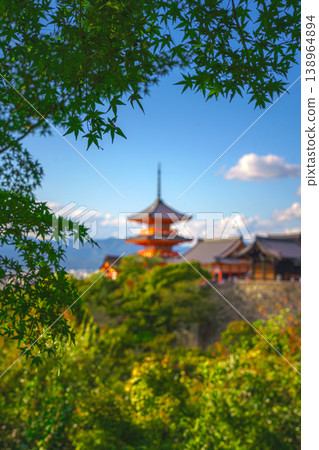 Kyoto, Japan - Oct 11 2024, vertical view through foliage of Kiyomizu-Dera temple complex with a pagoda, with a clear blue sky and a forest in foreground, at daytime, blurred, Kyoto, Japan Kyoto, Japan - Oct 11 2024, vertical view through foliage of Kiyomizu-Dera temple complex with a pagoda, with a clear blue sky and a forest in foreground, at daytime, blurred, Kyoto, Japan 138964894