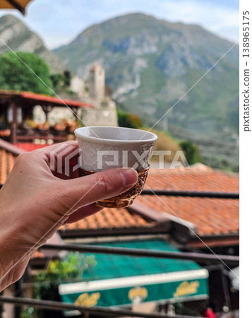 Close Up Hand Holding Traditional Coffee Cup in Ornate Copper Holder with Mountain and Red Roof Background Close Up Hand Holding Traditional Coffee Cup in Ornate Copper Holder with Mountain and Red Roof Background 138965175