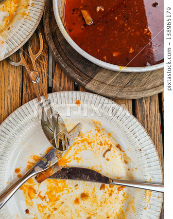 Top View of Dirty Plates with Red Sauce and Cutlery on Wooden Table After Meal 138965179