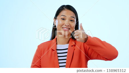 Portrait, smile and thumbs up with a business asian woman in studio on a blue background or support. Thank you, winner and emoji with a happy young employee in celebration of a goal or target Portrait, smile and thumbs up with a business asian woman in studio on a blue background or support. Thank you, winner and emoji with a happy young employee in celebration of a goal or target 138965312