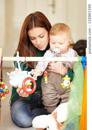 Mother, baby and playing with toys in living room for childhood development in home. Woman, son and hold with pacifier for care, love and support in bonding, together and future growth with games 138965399