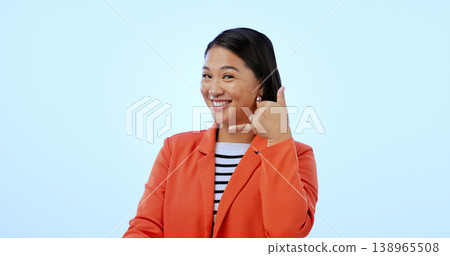 Woman, smile and call me with hand or contact us, networking and portrait in studio by blue background. Happy asian model, emoji and icon for communication, gesture and sign for telephone in mockup Woman, smile and call me with hand or contact us, networking and portrait in studio by blue background. Happy asian model, emoji and icon for communication, gesture and sign for telephone in mockup 138965508