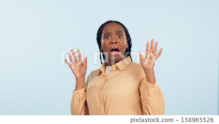 Black woman, fear and shock in studio portrait for anxiety, drama or secret with hands in air by blue background. African girl, wow and scared face for alarm, surprise or mind blown with announcement Black woman, fear and shock in studio portrait for anxiety, drama or secret with hands in air by blue background. African girl, wow and scared face for alarm, surprise or mind blown with announcement 138965526