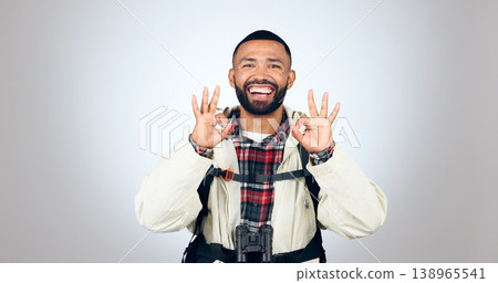 Perfect sign, hiker and portrait of man in a studio with a backpack for hiking adventure. Happy, smile and young male person from Mexico with ok hand gesture for camping isolated by gray background. Perfect sign, hiker and portrait of man in a studio with a backpack for hiking adventure. Happy, smile and young male person from Mexico with ok hand gesture for camping isolated by gray background. 138965541