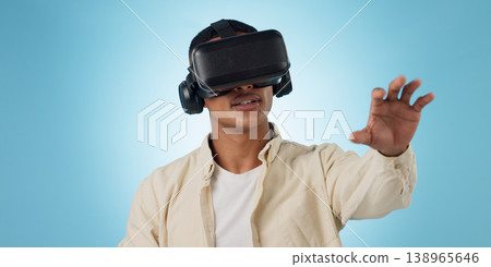 Man, student and VR or futuristic glasses for e learning, 3d software and user experience on blue background. Person with virtual reality vision, education and metaverse technology or games in studio Man, student and VR or futuristic glasses for e learning, 3d software and user experience on blue background. Person with virtual reality vision, education and metaverse technology or games in studio 138965646