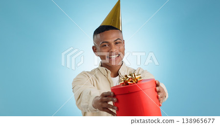 Portrait, happy man and party hat with gift in studio for celebration mock up on blue background in Cape Town. Model, giveaway and present for birthday, prize or event with competition, deal or offer Portrait, happy man and party hat with gift in studio for celebration mock up on blue background in Cape Town. Model, giveaway and present for birthday, prize or event with competition, deal or offer 138965677