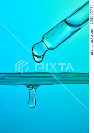 Pipette dropping liquid serum into blue water Pipette dropping liquid serum into blue water 138965783