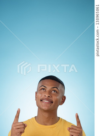 Man, face and pointing up to space in studio for advertising choice, decision or information about us on blue background. Happy model, thinking and show presentation of mockup, ideas and announcement Man, face and pointing up to space in studio for advertising choice, decision or information about us on blue background. Happy model, thinking and show presentation of mockup, ideas and announcement 138965861