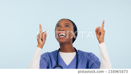 Smile, announcement and a nurse black woman pointing to space in studio on a blue background for healthcare. Medical, presentation and info with a happy young medicine professional showing mockup 138965873