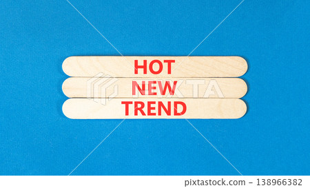Hot new trend words symbol. Concept words Hot new trend on beautiful wooden sticks. Beautiful blue background. Business and hot new trend concept. Copy space. 138966382