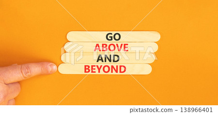 Go above and beyond symbol. Concept words Go above and beyond on beautiful wooden sticks. Beautiful orange background. Businessman hand. Business motivational Go above and beyond concept. Copy space. 138966401