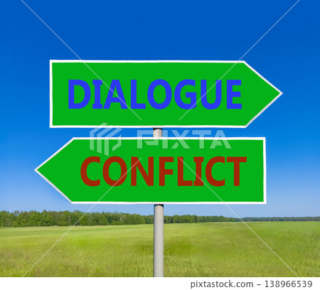 Dialogue instead conflict symbol. Concept words Dialogue and Conflict on beautiful green road sign. Beautiful blue sky green grass background. Social and dialogue instead conflict concept. Copy space. Dialogue instead conflict symbol. Concept words Dialogue and Conflict on beautiful green road sign. Beautiful blue sky green grass background. Social and dialogue instead conflict concept. Copy space. 138966539
