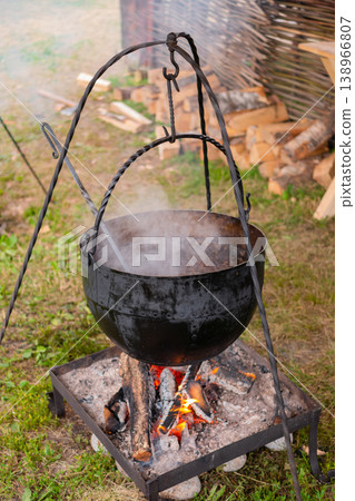 Preparing food in hanging pot over open fire - camping concept Preparing food in hanging pot over open fire - camping concept 138966807