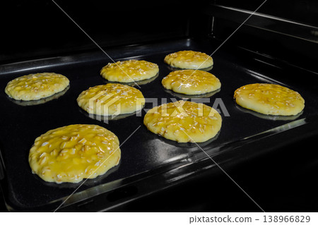 Cooking eight crunchy oatmeal cookies on metal sheet in oven 138966829