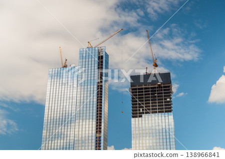 Yellow tower cranes and unfinished building construction 138966841