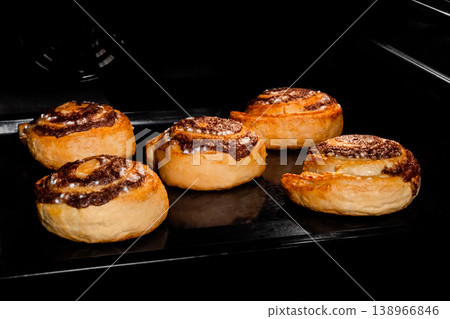 Five baked cinnamon buns in electric oven at home 138966846