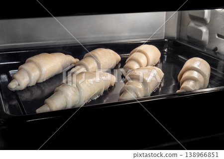 Six uncooked homemade croissants on tray in electric oven 138966851