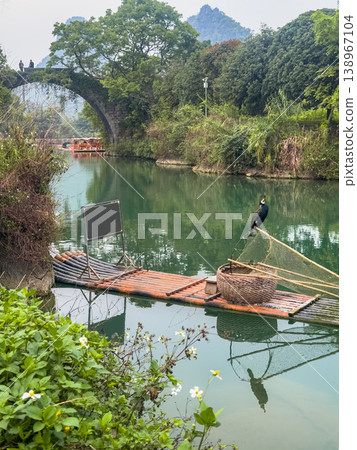 Guilin, China. Rustic wooden raft with cormorant floats on calm green river. Guilin, China. Rustic wooden raft with cormorant floats on calm green river. 138967104