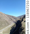 a road among the Landscape of the Caucasus Mountains, North Ossetia, Russia, bright summer day. Rolling green hills and rocky peaks under clear blue sky 138967250