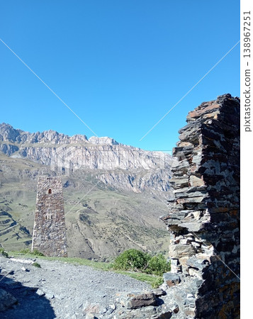 Ruins of the Kurta and Taga signal tower, North Ossetia, Russia. Crumbling stone walls of an ancient Alan watchtower on a green mountain slope 138967251
