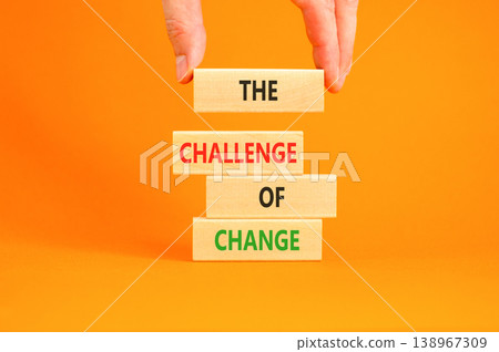 The challenge of change symbol. Concept words The challenge of change on beautiful wooden blocks. Beautiful orange background. Businessman hand. Business the challenge of change concept. Copy space. The challenge of change symbol. Concept words The challenge of change on beautiful wooden blocks. Beautiful orange background. Businessman hand. Business the challenge of change concept. Copy space. 138967309