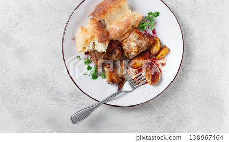 A plate with the remains of a pork kebab, there are no people. A plate with the remains of a pork kebab, there are no people. 138967464