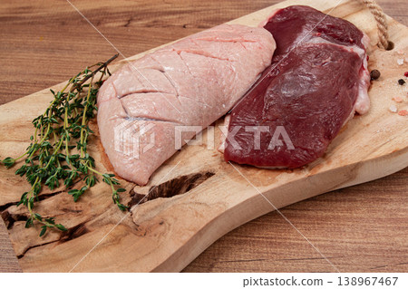 Fresh raw duck breasts, on a wooden chopping board, with herbs and spices, no people Fresh raw duck breasts, on a wooden chopping board, with herbs and spices, no people 138967467