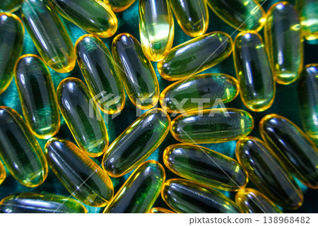 Omega 3 fish oil capsules close up on green background, glossy softgel supplements, healthcare and wellness concept 138968482