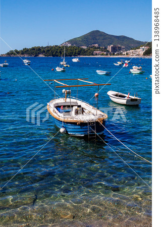 Vertical view of small boat floating on crystal clear sea water with visible seabed, Adriatic coast landscape, summer travel destination, peaceful marine scene Vertical view of small boat floating on crystal clear sea water with visible seabed, Adriatic coast landscape, summer travel destination, peaceful marine scene 138968485